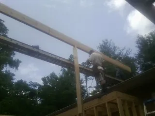 Carpenter setting a ridge beam over a new addition frame — Ice Dam Removal by Roofing Brothers in Popejoy
