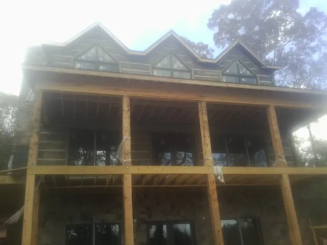 Dormers and porch framing on a large log home under construction — Roof Coating work by our crew in Popejoy