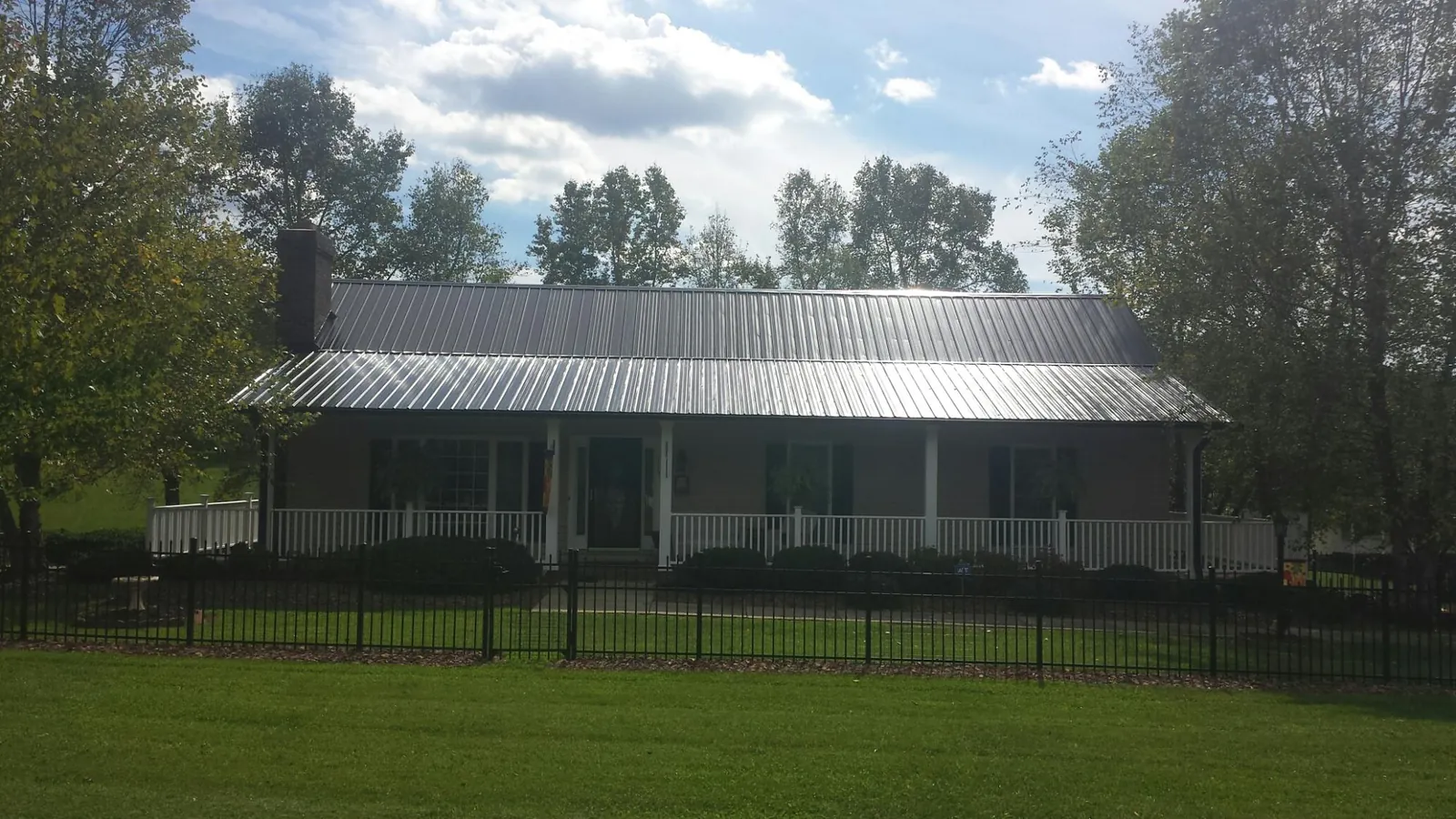 Gray metal roof on a brick ranch with a full width front porch — Gutter Guard Installation work by our crew in Popejoy