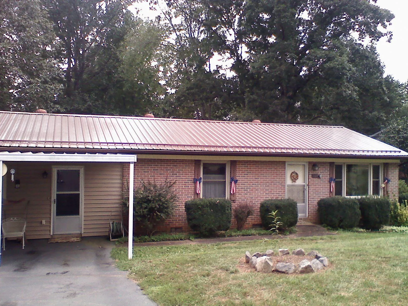 Bronze metal roof and carport on a brick ranch home — Roof Repair work by our crew in Popejoy