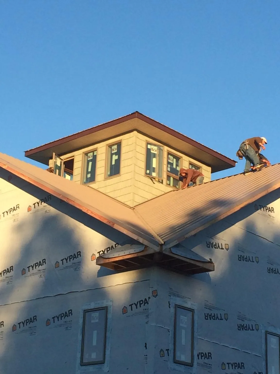 Roofers working around a rooftop cupola on a new metal roof at sunset — Roof Waterproofing in Popejoy by Roofing Brothers